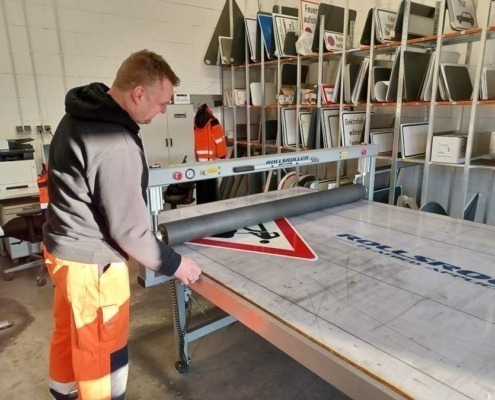 Mitarbeiter in der Werkstatt beim präzisen Bedrucken eines Verkehrsschildes, demonstriert handwerkliches Können und Sorgfalt.