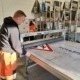 Mitarbeiter in der Werkstatt beim präzisen Bedrucken eines Verkehrsschildes, demonstriert handwerkliches Können und Sorgfalt.