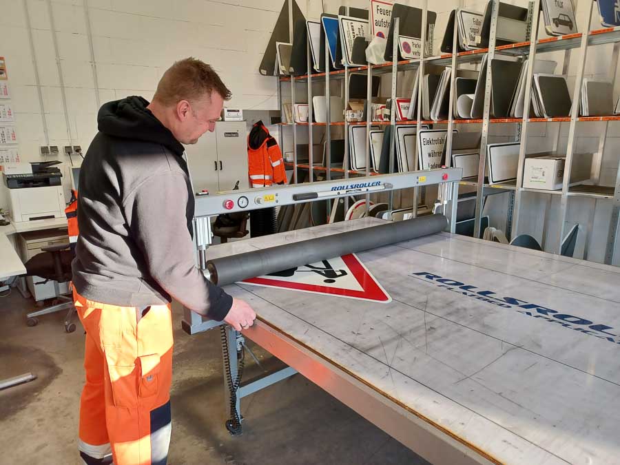 Mitarbeiter in der Werkstatt beim präzisen Bedrucken eines Verkehrsschildes, demonstriert handwerkliches Können und Sorgfalt.