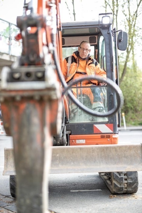 Mitarbeiter bei der Bedienung eines Baggers für Tiefbauarbeiten